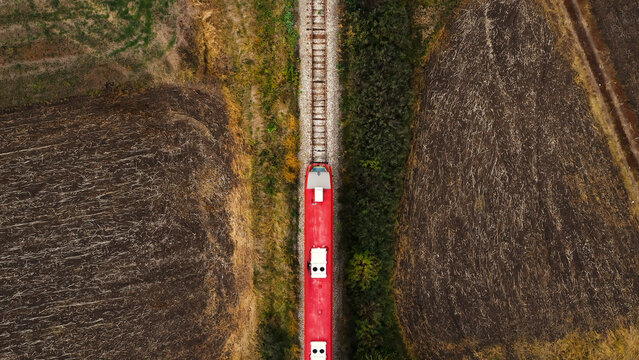 Aerial view of passenger train on railway through autumn countryside landscape, top view