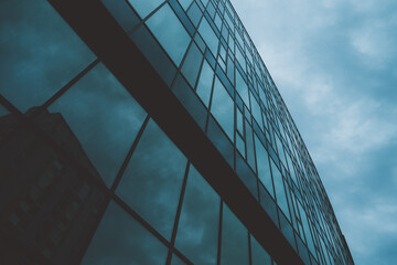 Low-angle perspective of a contemporary high-rise office building with reflective blue-tinted glass...