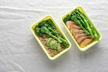 Minimalist takeout meal prep containers with quinoa, green broccolini, chicken breast and avocado