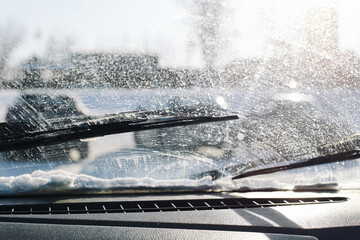 Dirty car windshield in winter conditions. Washer fluid spray and road grime on glass surface....