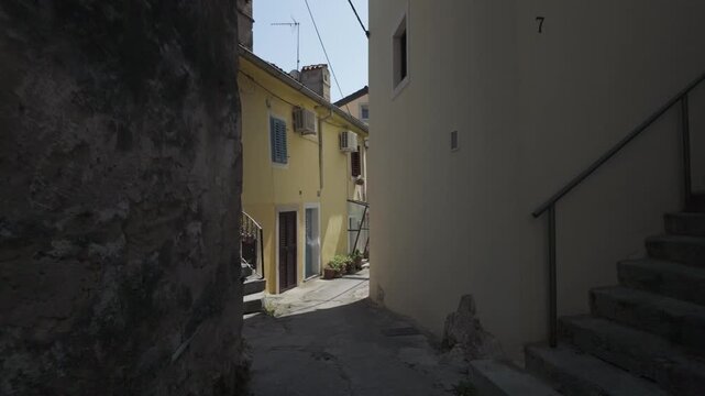 Walking along a street between romantic old Mediterranean houses houses in Volosko, Croatia. Real time building exterior with crumbling plaster and cute details. Sunny day in a historic old town.