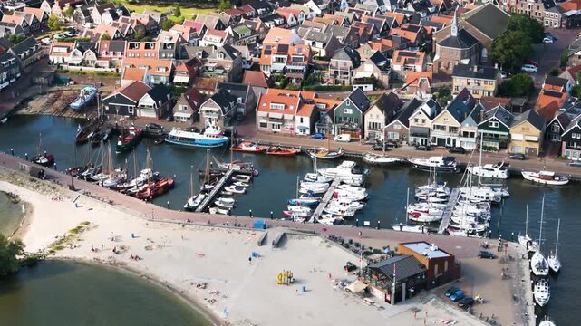various motorboats sailboats sit along floating docks next sandy beach traditional fishing vessels moored stone quays urk netherlands to top down aerial shot top-down marina 
