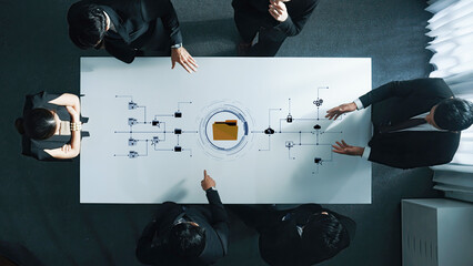 A professional business team engages in collaboration at a modern office table, discussing data analysis while showcasing digital technology graphics in a strategic meeting. Trope
