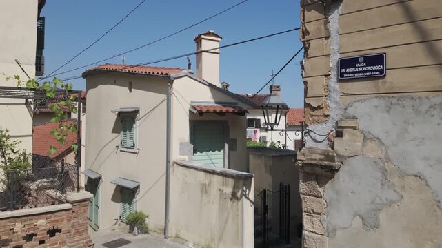Walking along a street between romantic old Mediterranean houses in Volosko, Croatia. Slow motion building exterior with crumbling plaster and cute details. Sunny day in the old town of a coastal city