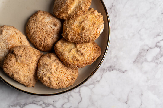 Freshly baked homemade Amaretti biscuits served on a ceramic plate. 