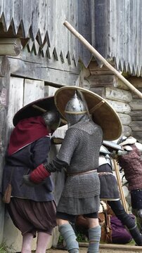 Medieval knights storm the wooden gate in the castle. Reconstruction of knightly battles
