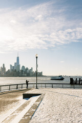 Fototapeta premium View of New York City skyline from waterfront with snow and a person taking photos on winter day