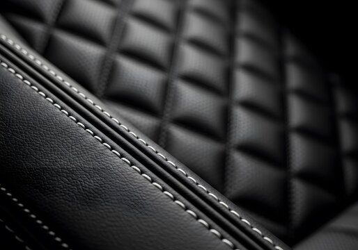 Close up of premium diamond quilted black leather upholstery, detailed white stitching on a luxury automotive interior, dark moody cinematic lighting