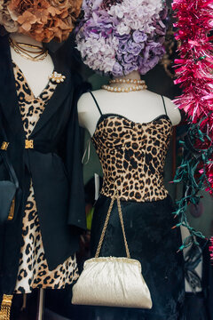 Fashion display features mannequins wearing leopard print outfits in a vintage consignment storefront during the daytime