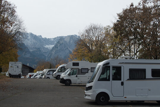 Wohnmobile auf Parkplatz im Herbst mit Bergkulisse