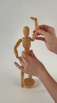 hand holding wooden mallet. Wooden mannequin takes first steps, moving like a poseable figure. This articulated mannequin and wooden model captures realistic movement, perfect for artists and dynamic 