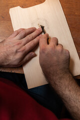 The master carves a Scandinavian pattern on a fir board