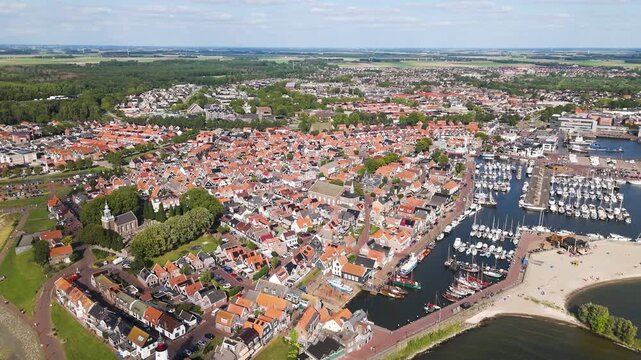 orange tiled rooftops prominent lighthouse overlook large harbor complex high panorama small sandy beach blue water urk netherlands reveals angle aerial harbour 