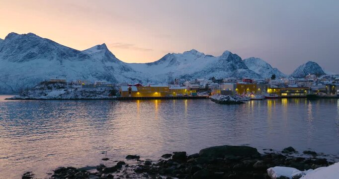 Hus&oslash;y im Winter zur blauen Stunde mit Blick in den Hafen, schneebedeckte H&auml;user und Boote im ruhigen Fjord, kalte Abendstimmung und klares arktisches Licht in Nordnorwegen