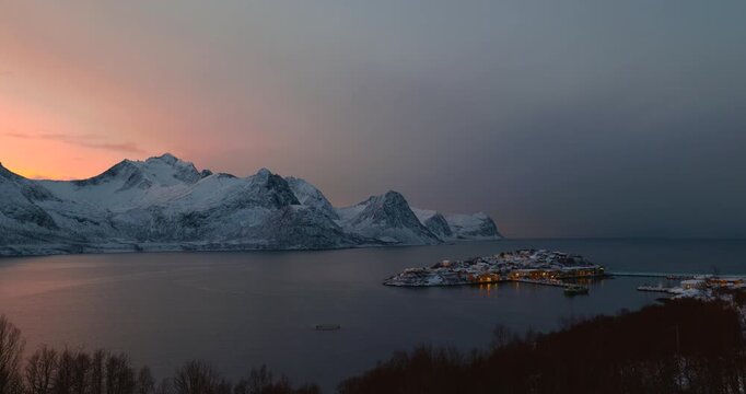 Hus&oslash;y im Winter zur blauen Stunde mit Blick in den Hafen, schneebedeckte H&auml;user und Boote im ruhigen Fjord, kalte Abendstimmung und klares arktisches Licht in Nordnorwegen