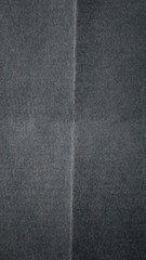 Fototapeta premium A macro photograph of dark gray paper featuring a pronounced outward fold running vertically across the surface.