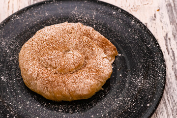 The delicate spiral-shaped sweet dough pastry is prominently featured. Deavily dusted with sugary powder and rich cinnamon. Traditional Turkish dessert provides a wonderful textured contrast