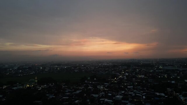 Aerial Drone View of Malang Cityscape, East Java, Indonesia, Featuring Traditional Red Roof Houses, Urban Landscape, and Misty Volcano Mountains in the Background at Sunrise