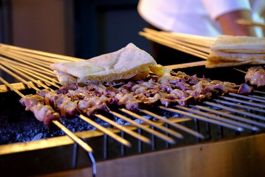 Close-up view of liver kebabs on skewers cooked over a wood fire in a kebab shop. Liver skewers grilled with tail fat . Turkish skewer kebab.
