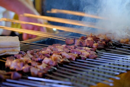 Close-up view of liver kebabs on skewers cooked over a wood fire in a kebab shop. Liver skewers grilled with tail fat . Turkish skewer kebab.