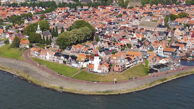 traditional red roofed homes green lawn surround iconic white lighthouse high paved seaside promenade urk netherlands angle shot view red-roofed flevoland high-angle 