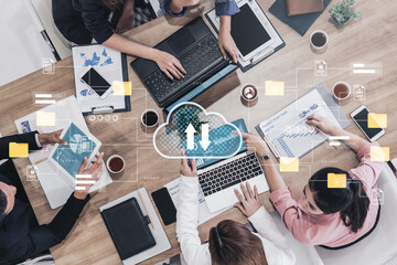 Overhead view of a team engaged in a collaborative meeting, exploring digital transformation concepts and cloud technology using laptops and tablets in an office workspace. Gantry