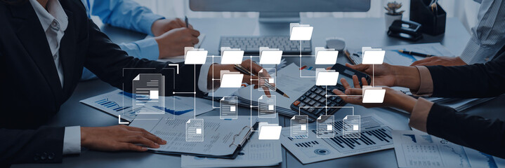 Professionals collaborate at an office desk, analyzing documents and data. The digital overlay represents a focus on strategy and teamwork in a modern corporate environment. Trope