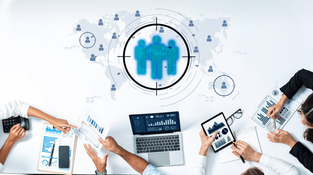 A diverse business team engages in collaboration around digital tools to analyze data and create marketing strategies with a focus on global connectivity and operations. Trope - Powered by Adobe