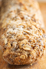 Rustic multigrain baguette topped with mixed seeds on wooden surface.