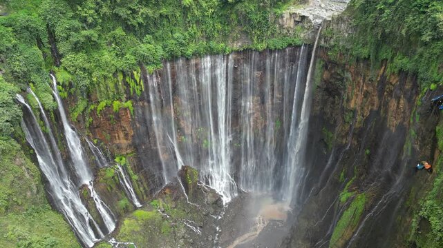 Majestic Tumpak Sewu Waterfall in Indonesia. Powerful water cascades in the tropical Java jungle, drone aerial view. Perfect for travel, nature background, and tourism editorial. Epic landscape.