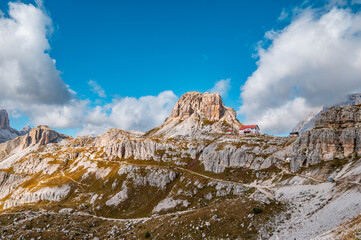 View of Antonio Locatelli hut under Tre Cime di Lavaredo and mountain group and blue sky, Dolomite Alps mountains, Trentino Alto Adige, Sudtirol, Dolomites, Italy. Hiking concept.
