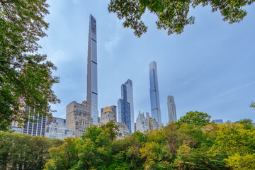 Fototapeta premium Modern skyscrapers of Billionaires' Row towering over Central Park greenery in New York City, featuring iconic supertall skyscrapers like Steinway Tower and Central Park Tower.