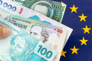 Fototapeta na wymiar Mercosur trade agreement with the European Union. Business concept. Banknotes of Brazil, Argentina, Paraguay, and Uruguay against the backdrop of the European Union flag