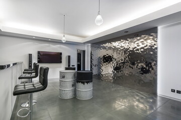 Modern interior of the living room for parties. A bar counter, original barrel tables, a large TV.