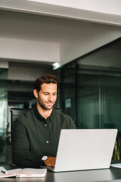 Latin young professional specialist latin hispanic business man working on laptop pc sitting at desk office. European businessman entrepreneur using computer technology app for work online. Vertical