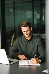 Focused young man student using laptop computer for business studying watching online webinar...