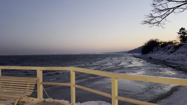 Cold winter seascape with dark blue water and gentle waves under an overcast sky. Minimalistic coastal landscape, calm and moody atmosphere, natural winter light. Concept of solitude, nature, cold cli