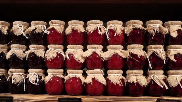 Rows of homemade berry preserves in rustic jars create a warm traditional market atmosphere with rich colors and natural textures highlighting seasonal sweetness and handcrafted culinary charm