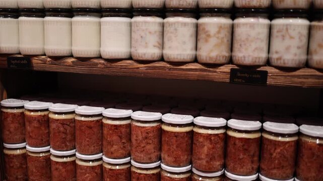 Rows of rendered pork fat and meat preserves in glass jars create a rustic store atmosphere with natural textures and warm tones highlighting traditional preparation and regional culinary heritage