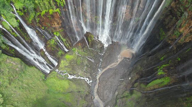 Majestic Tumpak Sewu Waterfall in Indonesia. Powerful water cascades in the tropical Java jungle, drone aerial view. Perfect for travel, nature background, and tourism editorial. Epic landscape.