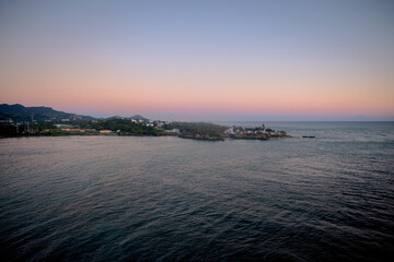 Tranquil coastal view of the Dominican Republic at dusk with soft pastel sky and calm ocean water, viewed from an elevated perspective.
