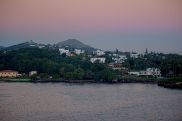 Tranquil coastal view of the Dominican Republic at dusk with soft pastel sky and calm ocean water, viewed from an elevated perspective.
