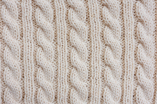 Cream colored cable knit texture with repeating pattern shown as abstract warm wool textile surface