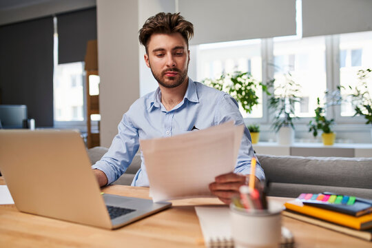 Concerned man reviewing domestic bills and financial debts at home office feeling worried about rising inflation.