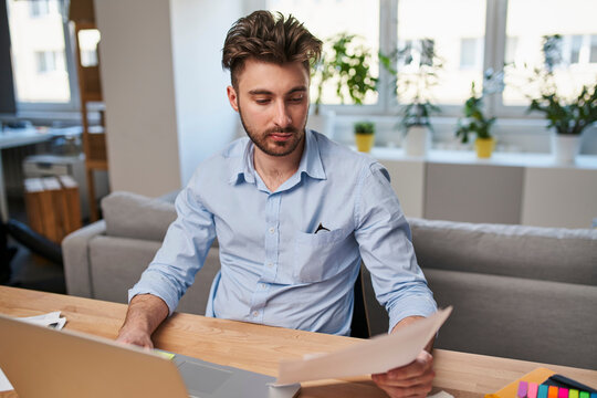Professional accountant reviewing financial statements and calculating taxes at home office desk during tax season.