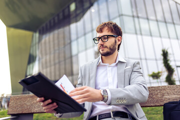 Young Businessman Reviewing Paper Documents on Bench