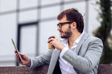 Young Businessman Using Tablet on Bench Outside Office