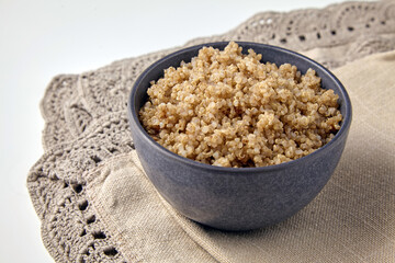 cooked quinoa porridge in a gray bowl on a brown linen tablecloth.
