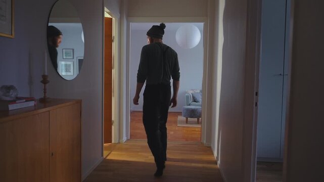 Man walking away indoors, winter clothing at home