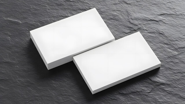 Two piles of thick white business cards mockups resting on dark textured slate stone surface overhead
